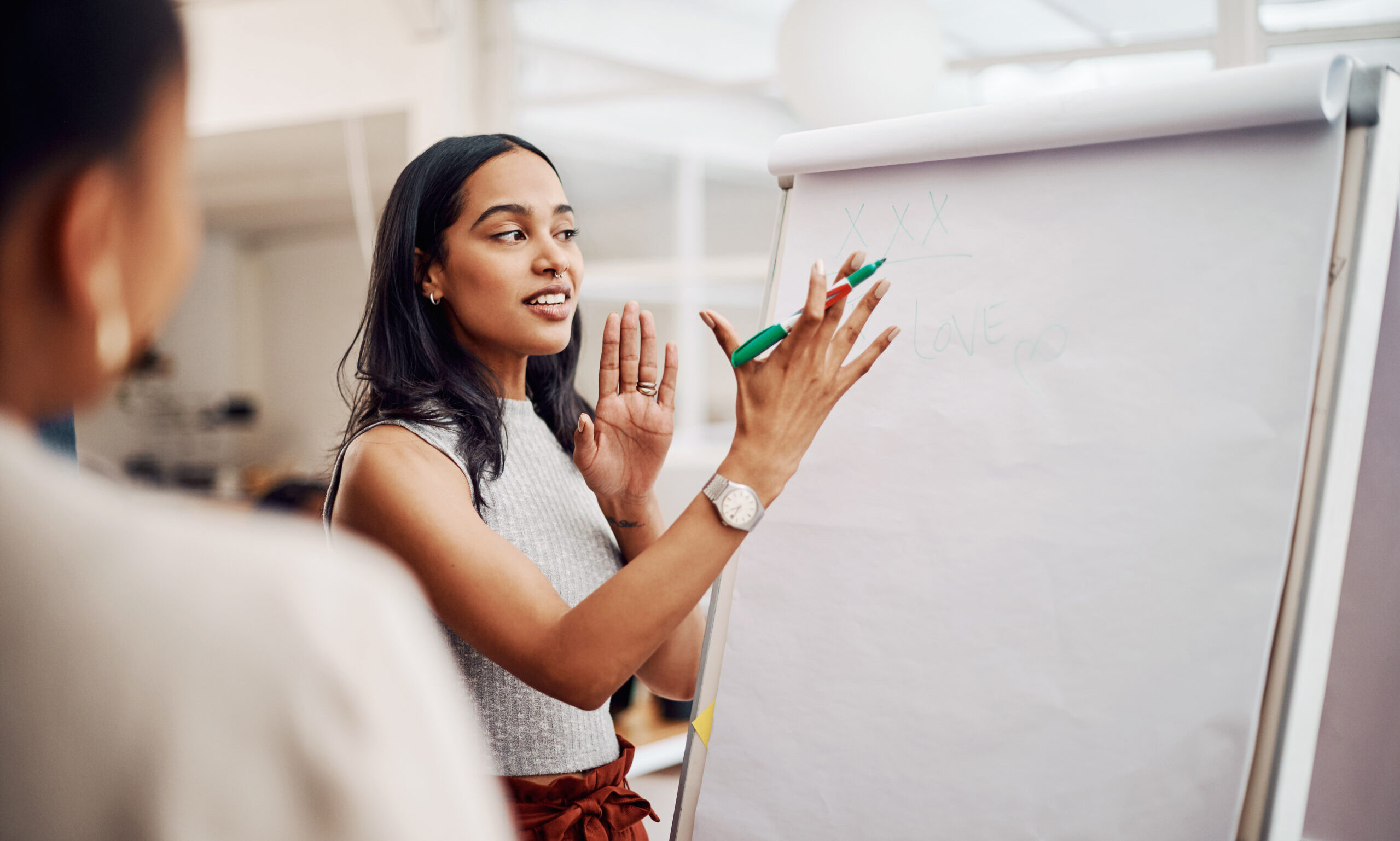 Woman, mentor and whiteboard in office for training, teaching and learning for skill or career development. People, employee and coach or leader at workshop with internship program and motivation
